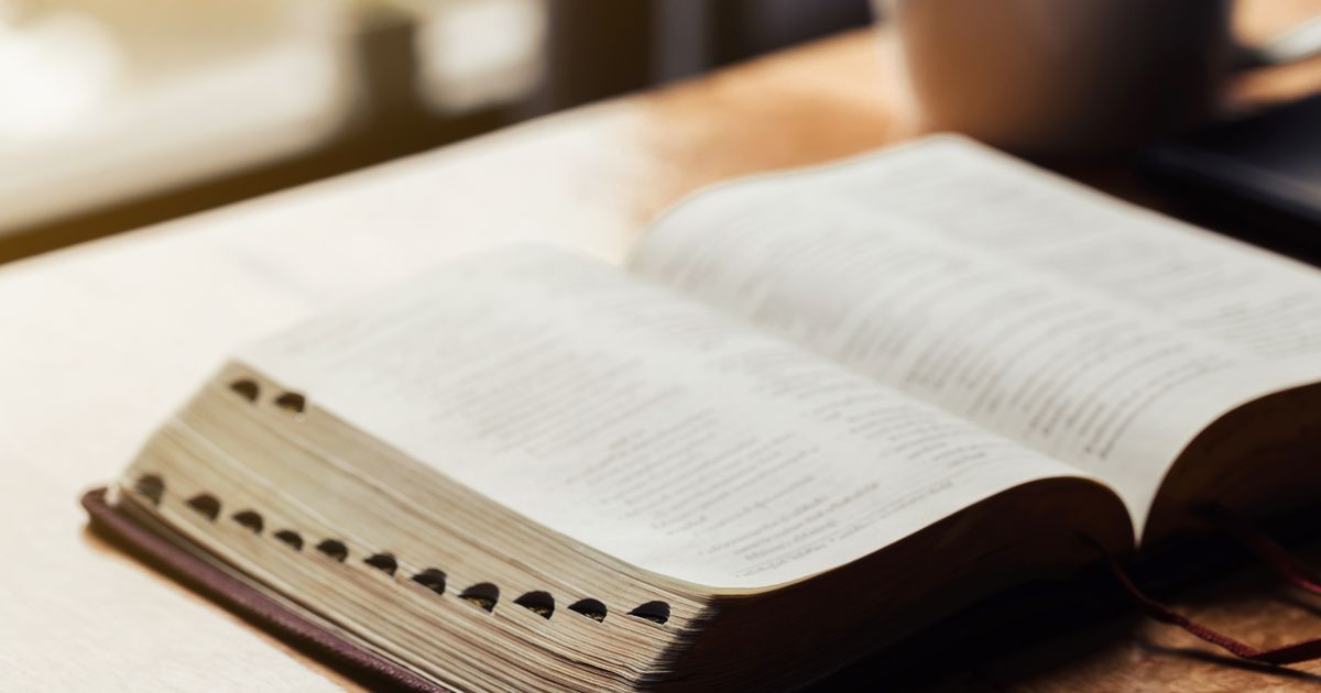 Open bible with a cup of coffee for morning devotion on wooden t