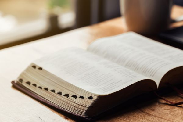 Open bible with a cup of coffee for morning devotion on wooden t